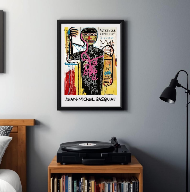 Puede incluir: Un cuadro enmarcado con una figura abstracta colorida con contornos negros, detalles rosas y un fondo amarillo y rojo. La impresi&oacute;n incluye el texto "JEAN-MICHEL BASQUIAT" en la parte inferior.