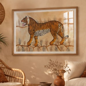 Op de afbeelding: Een ingelijste horizontale wandkunstprint met een gestileerde oranje en zwarte tijger die door een landschap met kleine, dunne bomen loopt. De tijger is in profiel afgebeeld met de tong zichtbaar tegen een warme, lichtbruine achtergrond.