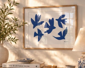 May include: A framed wall art print featuring five abstract blue bird silhouettes on a white background, signed Matisse in the bottom right corner. The artwork is enclosed in a light-toned wooden frame with a white mat border.