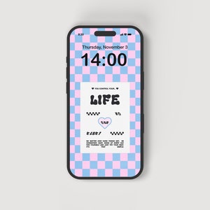 Puede incluir: Un teléfono inteligente muestra un fondo de pantalla con un patrón de cuadros rosas y azules. La pantalla de bloqueo muestra la hora, la fecha y un gráfico con la palabra "LIFE" y otro texto. El teléfono tiene un marco negro.