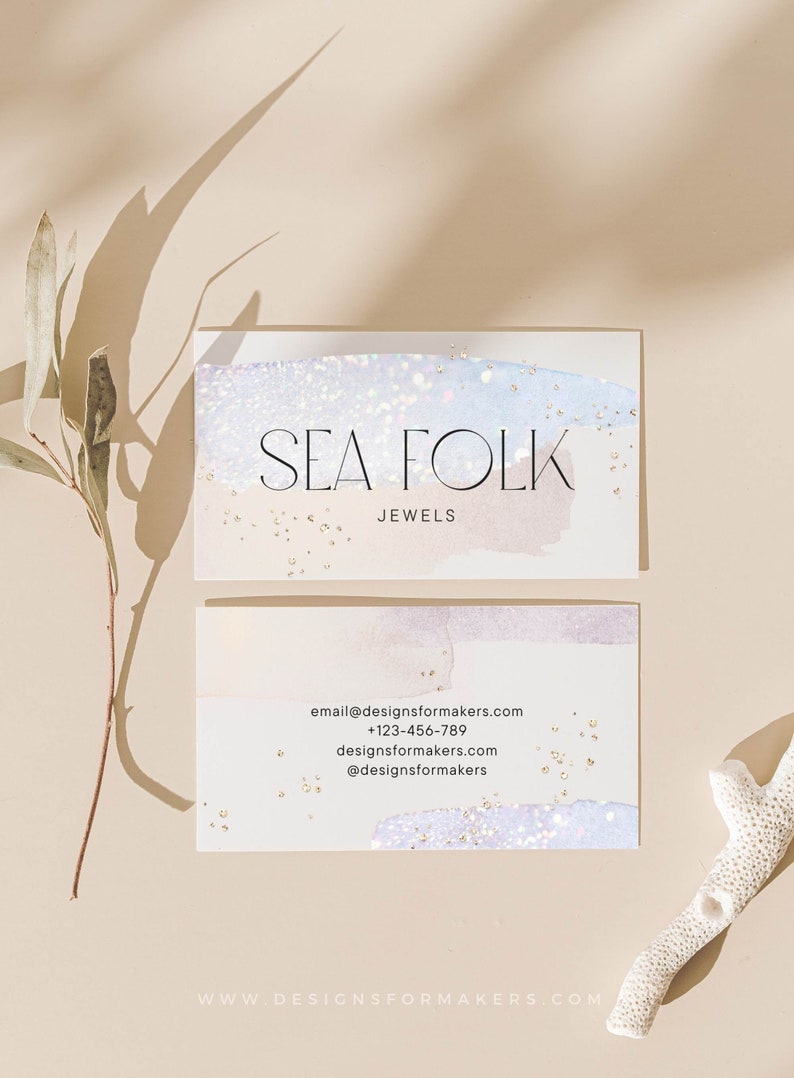 Op de afbeelding: Een visitekaartje met een aquarel achtergrond in tinten blauw en roze met gouden glitter. De tekst "SEA FOLK JEWELS" staat in zwart lettertype. De kaart bevat ook contactgegevens: email@designsformakers.com, +123-456-789, designsformakers.com, @designsformakers en www.designsformakers.com.