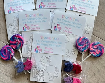 May include: A set of unicorn-themed party favors in clear plastic bags. Each bag contains a coloring page featuring a unicorn, a lollipop, and three unicorn-shaped crayons. The bags are tied with a pink ribbon and have a thank you tag that reads "Thank You For Celebrating My Birthday With Me! From, Cecilia."