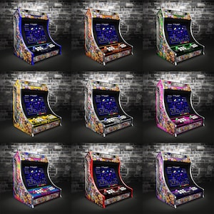 May include: Nine arcade cabinets with different colored designs. Each cabinet features a Pac-Man game screen and a joystick with buttons. The cabinets are arranged in three rows of three.