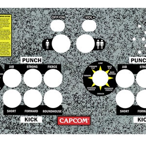 May include: A grey arcade control panel with a speckled texture. It has buttons labelled "PUNCH" and "KICK", directional controls, and text from "Street Fighter Champion Edition". The Capcom logo is visible.