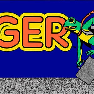 May include: A retro arcade game title card with the word "FROGGER" in large, orange and yellow letters. A green frog with a briefcase is running to the right, next to a black and white rock formation. The text "SEGA/Gremlin" is at the bottom of the card.
