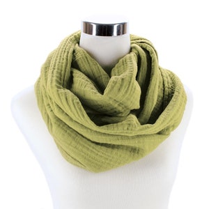 May include: A soft, green infinity scarf made of cotton gauze. The scarf is folded and draped around a white mannequin.