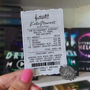 Peut inclure: Un autocollant rectangulaire blanc aux bords festonnés présentant un reçu imprimé de la librairie Kate Stewart. Le texte liste des articles dont Drive, Reverse, Bittersweet Mldy et Therapy Session avec leurs prix, finissant par Emotionally Wrecked.