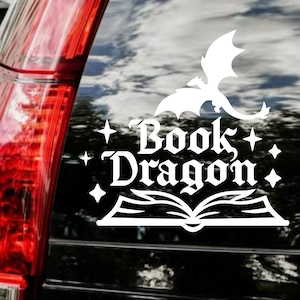 May include: White vinyl decal featuring a dragon above the words "Book Dragon" and an open book. The decal is designed to be applied to a car window or similar surface. The design includes stars and a whimsical font.
