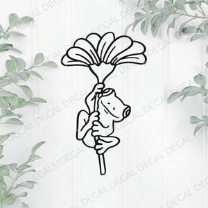 May include: Black and white decal of a cartoon frog clinging to a flower stem, holding a large flower. The frog has a smiling face and is outlined in black. The background is white with leafy green accents.