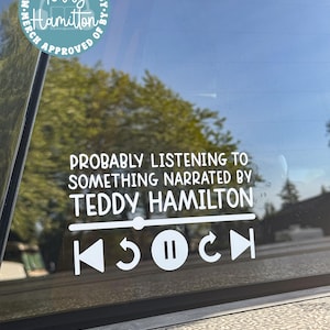 May include: White vinyl decal on a car window. The decal reads "PROBABLY LISTENING TO SOMETHING NARRATED BY TEDDY HAMILTON" with media player controls. A circular sticker above says "Teddy Hamilton Merch Approved".