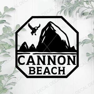 May include: Black and white decal featuring a mountain range, a flying bird, and the words "CANNON BEACH" in bold letters. The design is enclosed within a black octagon shape, suitable for outdoor use.