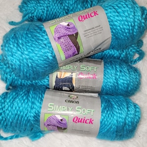 May include: Three skeins of Caron Simply Soft Quick yarn in a bright turquoise blue color. The yarn is labeled "Simply Soft Quick" and features a crocheted scarf on the label.