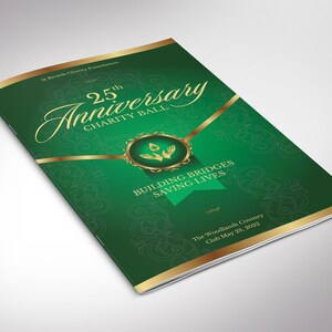 Könnte beinhalten: Eine grüne Broschüre mit goldenen Akzenten für den 25. Jahrestag des Wohltätigkeitsballs. Auf dem Cover steht "25th Anniversary Charity Ball", "Building Bridges Saving Lives" und das Datum 23. Mai 2022.