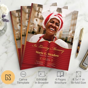 Op de afbeelding: Een stapel herdenkingsbrochures met een rood en goud ontwerp, met een foto van een lachende vrouw. De brochure bevat de tekst "In Loving Memory" en "Marie E. Meadow". Een gouden pen en nietmachine liggen naast de brochures.
