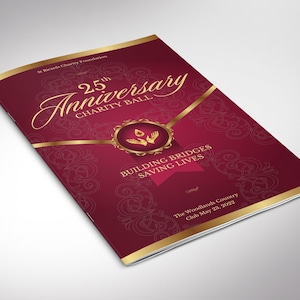 Op de afbeelding: Bordeauxrode brochure met gouden accenten, die de "25e verjaardag Charity Ball" promoot. De omslag toont een elegant lettertype en een decoratief embleem. Tekst bevat "Building Bridges Saving Lives" en evenementdetails.