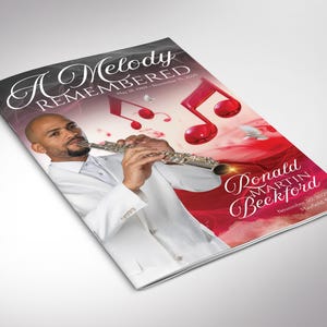 May include: A funeral program booklet titled A Melody Remembered featuring a person in a white suit playing a silver flute. The cover includes the text Ronald Martin Beckford, dates May 18, 1969 - November 15, 2025, and November 30, 2025, Mayfield, MN.
