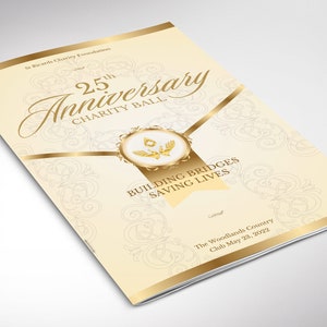 Puede incluir: Folleto color crema para el 25º Aniversario del Baile Benéfico. Los detalles y el texto en dorado incluyen "25th Anniversary Charity Ball", "Building Bridges Saving Lives" y "The Woodlands Country Club May 23, 2022".