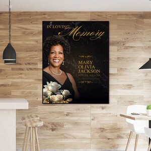 Puede incluir: Un cartel conmemorativo negro y dorado con una foto de una mujer con un vestido negro y flores blancas. El texto dice "En memoria cari&ntilde;osa Mary Olivia Jackson".