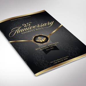 以下が含まれることがあります： 25th Anniversary Charity Ballの黒と金のプログラム冊子。表紙には、St Ricards Charity Foundation、25th Anniversary Charity Ball、Building Bridges Saving Lives Since 1992、The Woodlands Country Club May 23, 2022というテキストが記載されています。