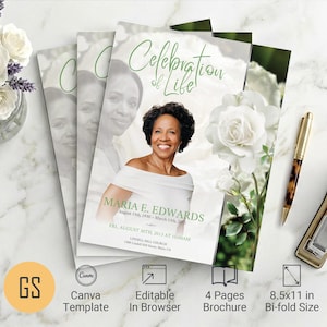 May include: A stack of bi-fold brochures with a floral and portrait design. The brochure features the text "Celebration of Life" and the name "Maria E. Edwards". A gold pen and stapler are on the white marble surface.