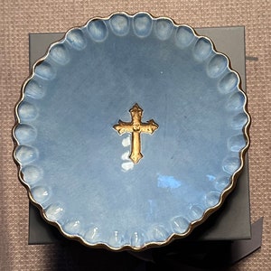 May include: A light blue ceramic dish with a gold rim and a gold cross in the center.