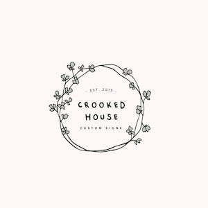 Op de afbeelding: Zwart-wit logo ontwerp met een krans van gestileerde bloemen en de tekst "CROOKED HOUSE CUSTOM SIGNS" en "EST. 2015".