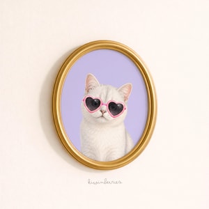 May include: A framed print featuring a white cat wearing pink heart-shaped sunglasses. The cat is set against a lavender background within a gold oval frame. The artwork has a whimsical and playful aesthetic.