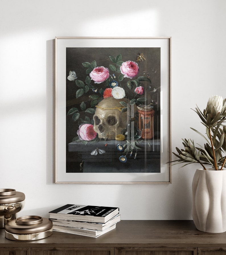May include: A still life painting featuring a human skull surrounded by pink roses, butterflies, and other flowers. The skull is adorned with a gold band and sits on a dark wooden surface.