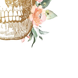 Puede incluir: Una calavera dorada con un dise&ntilde;o grabado detallado est&aacute; adornada con un grupo de delicadas flores de acuarela rosa y melocot&oacute;n y hojas verdes.