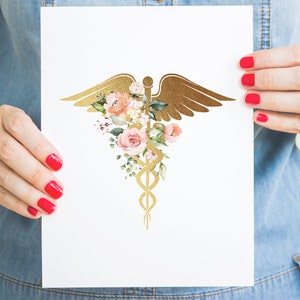 Puede incluir: Un s&iacute;mbolo de caduceo m&eacute;dico dorado con acentos florales rosas y blancos. El caduceo es un s&iacute;mbolo de la medicina y la atenci&oacute;n m&eacute;dica.
