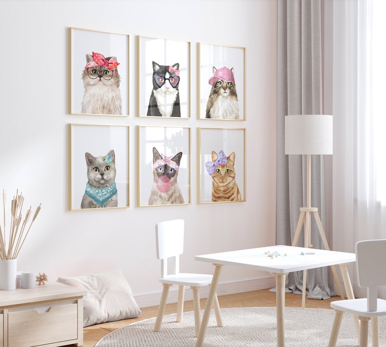 Puede incluir: Conjunto de seis impresiones enmarcadas con ilustraciones de acuarela de gatos que llevan varios accesorios. Los gatos llevan gafas de sol, sombreros y lazos. Las impresiones est&aacute;n en una habitaci&oacute;n blanca con una mesa y sillas blancas.