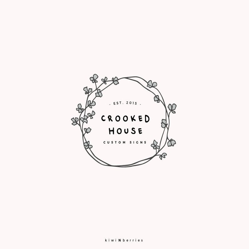 Op de afbeelding: Zwart-wit logo ontwerp met een krans van gestileerde bloemen en de tekst "CROOKED HOUSE CUSTOM SIGNS" en "EST. 2015".
