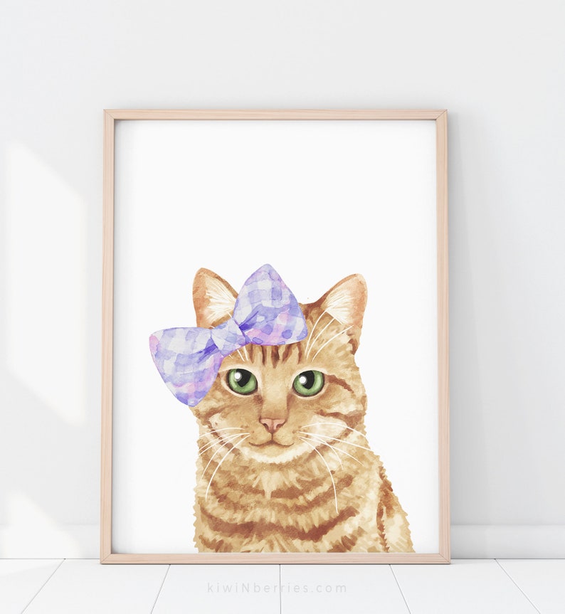 Puede incluir: Una pintura de acuarela de un gato jengibre con un lazo morado y rosa. El gato tiene ojos verdes y mira directamente al espectador. El fondo es blanco.