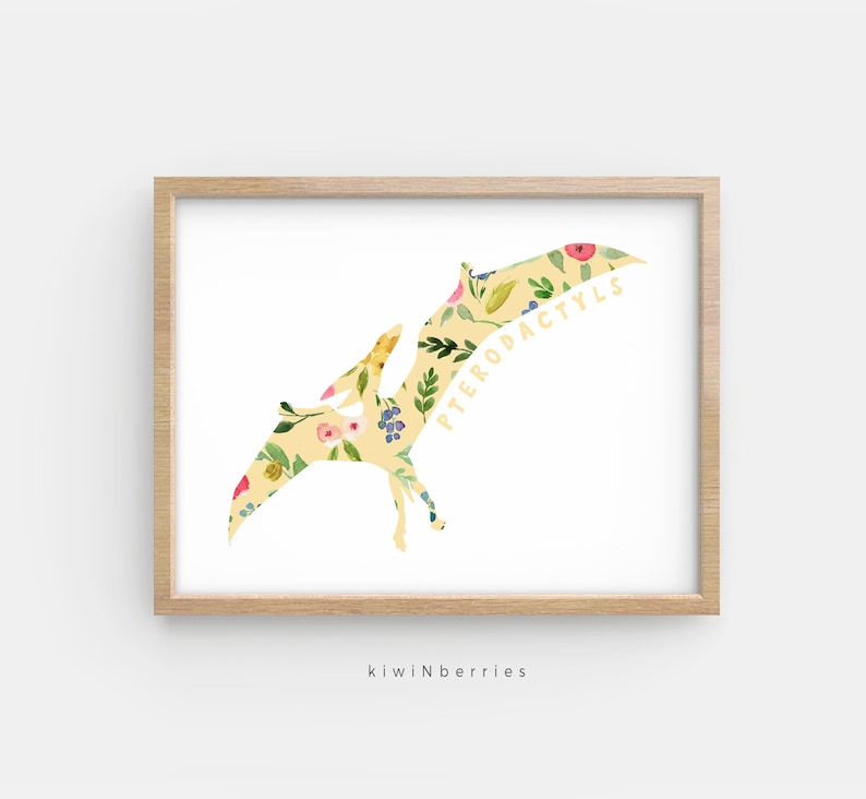 May include: A yellow floral print of a pterodactyl with the word "PTERODACTYL" written on the wing. The print is on a white background and is framed in a light wood frame.