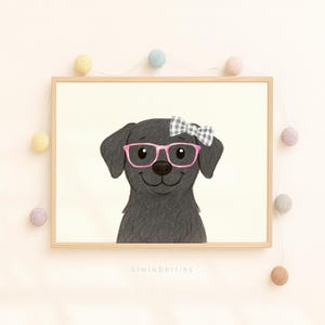 May include: A framed print featuring a smiling black Labrador Retriever wearing pink glasses and a gingham bow. The artwork has a light beige background and is decorated with a string of pastel-colored ball lights. The text "kiwiberries" is at the bottom.