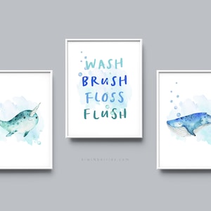Könnte beinhalten: Drei Aquarell-Drucke für ein Badezimmer. Der linke Druck zeigt ein Narwal, das in blauem Wasser mit Blasen schwimmt. Der mittlere Druck zeigt die Worte "WASH BRUSH FLOSS FLUSH" in Blau und Grün. Der rechte Druck zeigt einen Wal, der in blauem Wasser mit Blasen schwimmt.