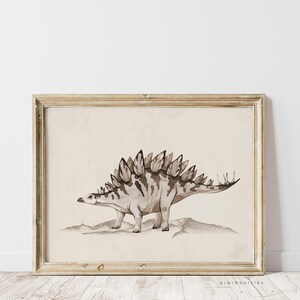 May include: A framed print of a watercolour illustration of a Stegosaurus dinosaur in shades of brown and beige. The dinosaur is depicted standing on a rocky surface.
