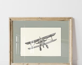 May include: A framed black and white illustration of a vintage airplane in flight. The airplane is a biplane with a propeller and two sets of wings. The illustration is on a cream-colored background and is framed in a light wood frame.