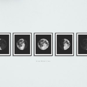 Peut inclure: Cinq impressions en noir et blanc encadrées de la lune dans différentes phases. Les impressions sont disposées en rangée sur un mur gris clair.