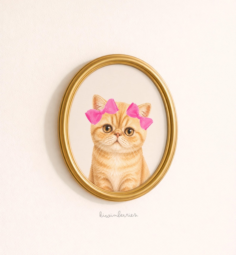 May include: An oval, gold-framed print featuring a cute orange tabby cat wearing pink bows. The cat has large, round eyes and a slightly grumpy expression. The print is set against a white background.