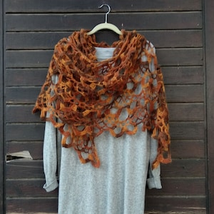 Könnte beinhalten: Ein graues Strickkleid mit einem weißen Tüllunterrock und einem braunen und orangefarbenen Häkeltuch, das darüber gelegt ist.