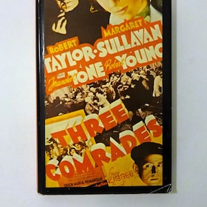 May include: A vintage movie poster for the film "Three Comrades" starring Robert Taylor, Margaret Sullavan, and Franchot Tone. The poster features a red and yellow color scheme with the title in large, bold letters.