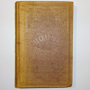 May include: A vintage book with a textured, tan cover. The cover features embossed decorative corner designs and the words "HOUSE DOCUMENT" in a central, arched layout. The book's edges show wear, indicating its age.