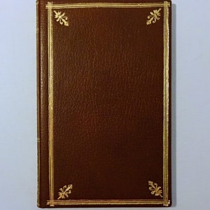 May include: A brown leather-bound journal with gold accents and decorative floral designs on the cover.