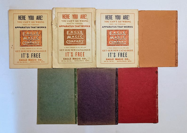 Puede incluir: Una colecci&oacute;n de siete folletos y libros antiguos. Tres folletos de color crema presentan el texto HERE YOU ARE! YOU CAN'T GO WRONG WHEN YOU PURCHASE APPARATUS THAT WORKS EAGLE MAGIC COMPANY. Cuatro libros de colores s&oacute;lidos son verde, morado, rojo y tostado.