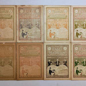 Puede incluir: Ocho n&uacute;meros antiguos de la revista The Eagle Magician de 1918, dispuestos en dos filas. Cada portada de color tostado presenta ilustraciones de magos realizando trucos, el t&iacute;tulo, mes, a&ntilde;o y el texto impreso Price 10-Cents.