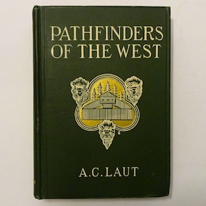 May include: A green hardcover book titled "Pathfinders of the West" by A.C. Laut. The cover features a gold illustration of a cabin in the woods with three buffalo heads.