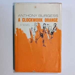 May include: A vintage paperback book titled "A Clockwork Orange" by Anthony Burgess. The cover is orange with white text and a black and white illustration of figures. The book is a novel.