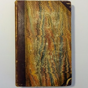 May include: A vintage book with a marbled cover in shades of brown, yellow, and green. The book has a dark brown spine with a gold-colored title.