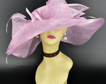 May include: A large, wide-brimmed hat made of pink straw with a delicate, ruffled design. The hat is worn on a mannequin's head, and the brim of the hat covers the mannequin's face.